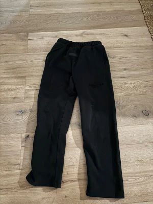 Essentials byxor - Ett par svarta essentials byxor väldigt sköna kan användas till att bara ha de som mjukisar till att ha de till lite finare outfits, lågt pris eftersom att de har en liten fläck som man inte ser på långt håll.