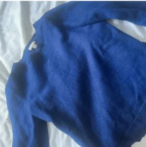 Blå stickad tröja från Gap - En klassisk blå stickad tröja från Gap i mjuk ull. Tröjan har rund halsringning och långa ärmar, perfekt för kyliga dagar. Enkel och stilren design som funkar till det mesta. Snyggt ribbade muddar vid ärmslut och nederkant.