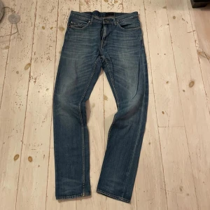 Tiger of Sweden Blå jeans modell Pistolero 32/32  - Snygga blå jeansbyxor från Pistolero i klassisk tvätt med lätt slitning. Modellen har raka ben, fem fickor och orangea sömmar. Perfekta för dig som gillar en tidlös och avslappnad look. Tillverkade i jeansmaterial och passar till många olika stilar.