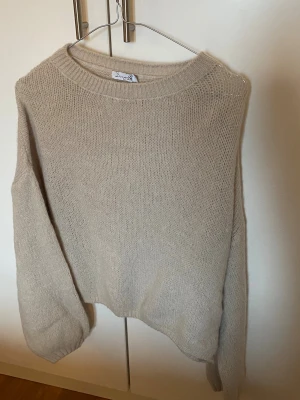  Stickad tröja från Design by Si OBS!! se beskrivning  - Mysig beige stickad tröja från Design by Si med rund hals och långa ärmar.  Miti knit i Beige.    OBS!!!! Den är råkat tvättad vilket gjort att den blivit bredare. XS/S