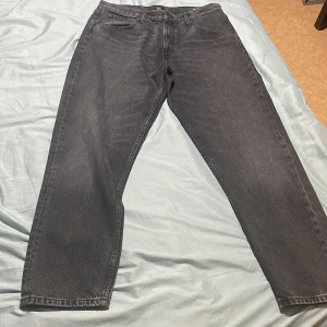 Grå jeansbyxor från Lee - Snygga grå jeansbyxor från Lee med klassisk design. Byxorna har en normal passform och är tillverkade i slitstarkt denim. Perfekta för en stilren look.