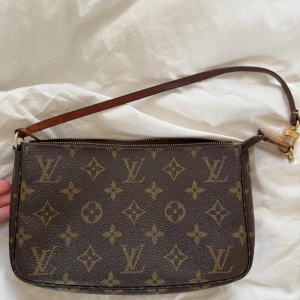 Louis Vuitton pochette - Sjukt snygg och tidlös Louis Vuitton pochette. Väskan är från 2002 och gjord i Spanien, serienummer CA0032. Orginalkvitto, dustbag och extra band medföljer. Vintage men fint skick på insida och inga synliga fläckar på monogrammen. En tråd är lite lös och dragkedjan ar lite sönder men fungerar som vanligt (se bild)