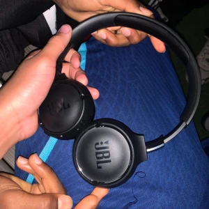JBL On-Ear Hörlurar - Snygga svarta JBL on-ear hörlurar i gott skick. Bekväma öronkuddar och justerbar bygel. Perfekta för musik, spel eller samtal. Inga synliga repor eller skador, fungerar utmärkt. Stilren design och bra ljudkvalitet.