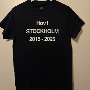 Svart Hov1 Stockholm t-shirt - Svart t-shirt från Hov1 med vit text fram och bak. Framsidan har tryck med 'Hov1 STOCKHOLM 2015-2025' och baksidan listar turnédatum och platser samt texten 'Vi Dansar Vidare I Livet'. 