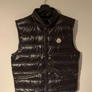 Moncler Gui Väst - Säljer nu min Moncler Gui väst då den har blivit för liten för mig. Äkta och Scan å tagg funkar har tappat bort dust bag å allt men köpt på merchsweden. Dragkedjan är lite trasig men går att använda om man drar upp den nedre dragaren först. Skicket är 9/10 Inga defekter 