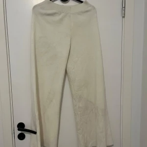 Vita stickade mjukisbyxor - Mysiga vita stickade mjukisbyxor med bred resår i midjan. Byxorna har en rak passform och är perfekta för en chill och avslappnad stil. Supermjuka och sköna att ha på sig, passar perfekt till hemmadagar eller när du vill vara extra bekväm.