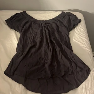 Mörk grå blus från Saint Tropez - Mörk grå blus från Saint Tropez i flowy modell med korta puffärmar och rundad halsringning. Blusen har knappar framtill och resår i midjan baktill. Lite stor i strl, har vanligtvis S/M och denna passar fint! Hör av er vid frågor/intresse💕 