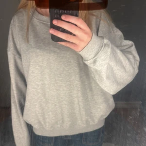Grå sweatshirt i oversized modell - Enkel och stilren grå sweatshirt med rund hals och breda muddar vid ärmslut och nederkant. Oversized passform som ger en avslappnad vibe. Perfekt att matcha med jeans eller leggings för en chill look.