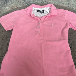 Rosa pikétröja från Sebago XS - Säljer en rosa pikétröja från Sebago i storlek XS. Tröjan har klassisk krage, knäppning med fyra knappar och ett broderat vitt ankare på bröstet. Tillverkad i mjuk bomull, perfekt för en chill och sportig look. använt fåtal gånger
