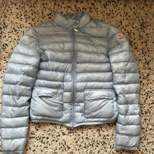 Ljusblå dunjacka från Moncler - Säljer en snygg ljusblå dunjacka från Moncler med fickor där framme och hög krage. Den är i storlek S men passar även Xs och M skulle jag påstå. Nypris är ungefär 94000kr , bra skick 🥰