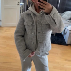 Grå ulljacka från Even&Odd, S - Säljer en snygg grå jacka från Even&Odd i ullmix. Jackan har klassisk jeansjacke-look med två bröstfickor, stora knappar framtill och krage. Perfekt för lager-på-lager. Superenkel att styla till allt.