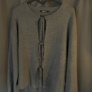 Grå kofta med knyt från Gina Tricot - Grå kofta från Gina Tricot med knyt framtill. Modellen är långärmad med lite vida ärmar. Jätte fin stickad kofta och perfekt till hösten. Helt slutsåld, säljs för att den inte kommer till användning. Kontakta för egna bilder.