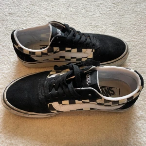 Vans Old Skool Checkerboard sneakers - Säljer ett par klassiska Vans Old Skool sneakers i svart och vitt checkerboard-mönster. Skorna har svart mocka framtill och på hälen, vita sidor med rutigt tyg och svarta snören. Ikonisk vit Vans-sidostrip och platt sula. Extra vita skosnören medföljer.
