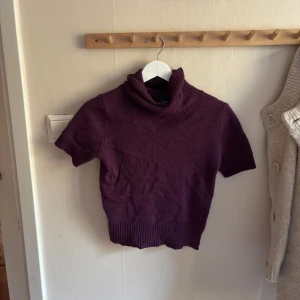 Lila polotröja från Hennes XS - Kortärmad polotröja i mörklila från Hennes. Tröjan har ribbade detaljer vid krage, ärmslut och nederkant. Perfekt för lager-på-lager.