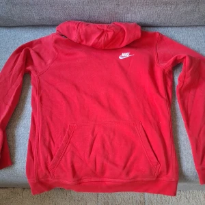 Röd Nike hoodie XL med huva - Röd hoodie från Nike i storlek 158-170 cm barnstorlek (XL). Tröjan har huva, känguruficka och är tillverkad i mjuk bomull. Inga skador eller hål på den.
