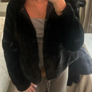 Svart pälsjacka  - Säljer en svart pälsjacka från ONLY med mjuk och fluffig yta. Jackan har en klassisk krage, långa ärmar och stängs med knappar framtill. Perfekt för dig som vill ha en stilren och mysig look under kyliga dagar.