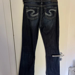 Lågmidjade jeans - Säljer dessa mörkblå lågmidjade jeans. Fian detaljer på bakfickorna samt ljusa sömmar. Inga tecken på slitage eller användning. I storleken 28/33