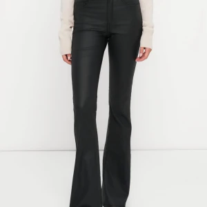 Skinnbyxor - Snygga svarta byxor i skinnimitation med bootcut-ben och hög midja. Byxorna har klassiska fickor fram och bak samt bälteshällor. Perfekta för dig som vill ha en trendig och edgy look med en smickrande passform. Storlek M i midja och 34 i längd!