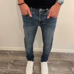  Tiger of Sweden slim jeans - Snygga blå jeans från Tiger of Sweden i modellen Evolve. Klassisk femficksdesign med bruna kontrastsömmar och läderpatch bak i midjan. Jeansen är tillverkade i Italien och har en slim passform som funkar till det mesta. Perfekta för dig som gillar stilrena och tidlösa jeans.