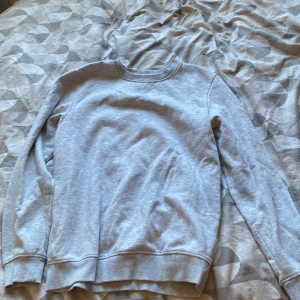 Ljusgrå sweatshirt från 157 - En basic ljusgrå sweatshirt från 157 med rund halsringning och ribbade muddar vid ärmslut och nederkant. Perfekt för dig som gillar en enkel och clean stil. Mjuk insida som gör den extra skön att ha på sig. Den va på kill avdelningen men den passar bra på tjejer också.