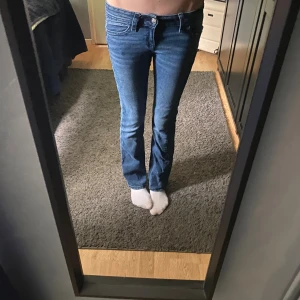 Blå bootcut jeans från Gina Tricot - Snygga jätte lågmidhade blå jeans från Gina Tricot i modell bootcut med klassiska fem fickor och coola detaljer på bakfickorna. Jeansen är väldigt bra skick och endast använda några få gånger. Storleken är 158/tall❤️