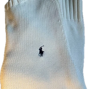 Vit stickad tröja från Ralph Lauren - Vit stickad tröja från Ralph Lauren i 100% bomull. Klassisk modell med rund halsringning, ribbade muddar och diskret broderad logga på bröstet. Perfekt för dig som gillar stilrena och tidlösa plagg.