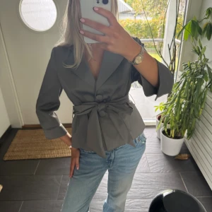 Grå kavaj med knytning - Trekvartsärmad blus / kavaj. Storlek 42 men skulle absolut säga att den är mindre i storleken 