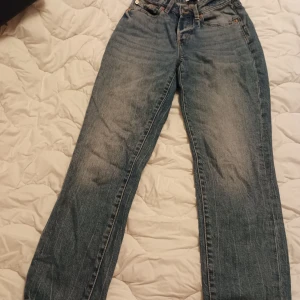 Blå jeans från 157 med raka ben - Klassiska blå jeans från 157 med raka ben och hög midja. Jeansen har fem fickor, knäppning med knappar och snygga slitningar för en avslappnad look. Tillverkade i robust denim med bruna detaljer vid fickorna och läderpatch bak i midjan.
