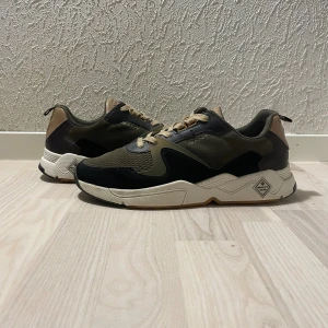 Gant skor herr - Snygga chunky sneakers från Gant i grönt, svart och beige med vita detaljer. Skorna är i storlek 45 och har ett nypris på runt 1600kr. Skriv gärna vid fler funderingar eller frågor:)