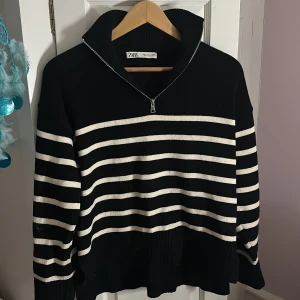 Randig stickad half zip-tröja från Zara - Svart och vit randig stickad tröja från Zara med half zip-dragkedja och hög krage. Oversized fit med långa ärmar och ribbade muddar. Snygga slitsar i sidorna för extra detalj. Perfekt för lager-på-lager under höst och vinter. Använd för 2 år sen 3-4 gånger ‼️