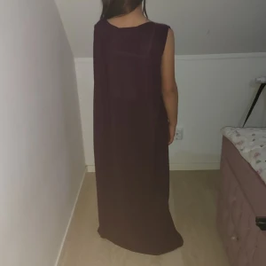 Vinröd glittrig långklänning med bälte - Säljer en vinröd långklänning med glittriga paljetter och broderade detaljer. Klänningen har korta ärmar, djup v-ringning och medföljande matchande bälte med glittrigt spänne. Sitter figurnära och har en elegant släp. Perfekt för dig som vill sticka ut.