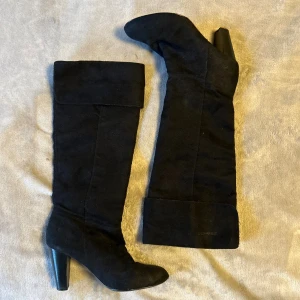 Svarta mocka stövlar klack 39 - Supersnygga mocka stövlar från SthlmDG i storlek 39. Med klack. Perfekta nu i höst🍁 Bra skick förutom en slitning längst fram på ena stöveln men syns knappt och slitna sulor under och ena ”pluppen” saknas på ena klacken(se bilder)❤️