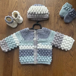 Virkat Babyset Nyfödd - Kofta, mössa, tossor & vantar - Ett virkat set som består av kofta med knappar, mössa, tummvantar & små tossor. Tillverkat med 45% bomull & 55% akrylgarn. 