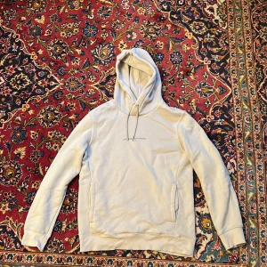 Beige hoodie L'Atelier Archives H&M S - Snygg beige hoodie från H&M med L'Atelier Archives Paris-tryck på bröstet. Tröjan har huva med snörning, ribbade muddar och en clean look. Perfekt för chill dagar och enkel att matcha med jeans eller joggers.