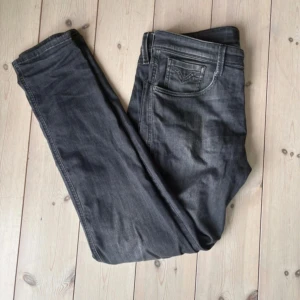 Replay Anbass Slim Fit jeans grå - Snygga Replay Anbass jeans i slim fit med klassisk femficksdesign. Färgen är mörkgrå med lätt tvättad look och raka ben. Märkespatch bak i midjan och diskreta sömmar. Perfekta för dig som gillar stilrena och moderna jeans.