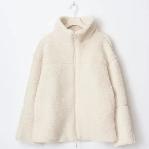 Beige teddyjacka med dragkedja - Mysig teddyjacka i beige med hög krage och hel dragkedja framtill. Jackan har en fluffig och mjuk yta som ger en chill vibe och passar perfekt när du vill hålla dig varm. Enkel och stilren design utan synliga detaljer eller mönster.