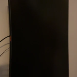 Okänd datorskärm - Stor datorskärm med böjd design, svart färg. Skärmen är avstängd på bilden och inga synliga märken eller logotyper kan identifieras. Inga uppenbara repor eller skador syns. Perfekt för gaming eller arbete.