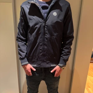 Mörkblå vindjacka från Henri Lloyd stl M - Snygg mörklblå vindjacka från Henri Lloyd i stl M.  Passar 180 cm lång. Vid funderingar är det bara höra av sig!