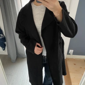 Svart kappa från Cosy House - Stilren svart kappa från Cosy House i storlek S med snöre i midjan och fickor 