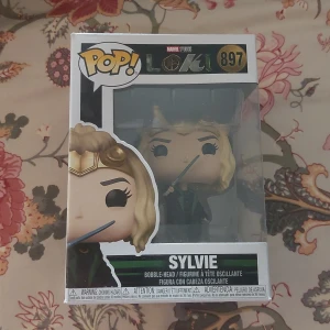 Funko Pop! Sylvie #897 Loki - Funko Pop! figur av Sylvie från Marvels Loki-serie, nummer 897. Figuren är i originalförpackning och ser ut att vara i nyskick, perfekt för samlare. Inga synliga skador på kartongen.