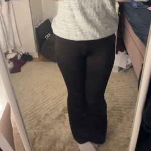 Svarta bootcut byxor med snörning - Säljer ett par svarta bootcut byxor med snygg snörning i midjan som kan korsas framtill. Byxorna har en mjuk och stretchig känsla, perfekt för dig som gillar en trendig och bekväm look. Passar dig som vill ha en cool siluett med lite utsvängda ben. Priset kan diskuteras 