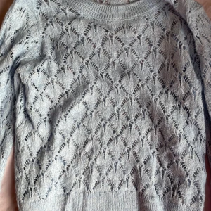 Ljusblå stickad tröja från JDY - Superfin ljusblå stickad tröja från JDY med ett genombrutet, mönstrat stickat material. Tröjan har rund halsringning och långa ärmar, perfekt för lager-på-lager. Snygg till både jeans och kjol för en chill look.