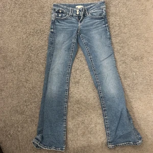 Blå bootcut jeans från Gina Tricot - Snygga blå jeans från Gina Tricot i storlek 152. Modellen har klassisk bootcut med lätt utsvängda ben och normal passform. Jeansen har fem fickor, bälteshällor och kontrastsömmar. Perfekt för dig som gillar retrovibbar och bekväm stil.