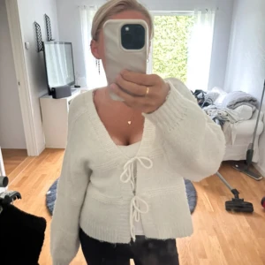 Vit stickad kofta med knyt från BikBok - Supermysig vit stickad kofta från BikBok i storlek S. Koftan har v-ringning och två knyt framtill. Perfekt att slänga på sig över ett linne eller t-shirt.