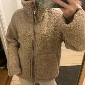 Beige teddyjacka med dragkedja - Intressekoll på denna populära beigea teddyjackan från H&M med hög krage och två stora fickor framtill. Perfekt för kalla dagar och enkel att matcha med jeans. Prislapp kvar. Helt ny.