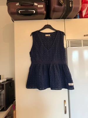 Mörkblå ärmlös blus Odd Molly - Supersöt mörkblå blus från Odd Molly med broderade blommor och v-ringning. Modellen är ärmlös och har en volang nedtill som ger en skön och flowy känsla. Perfekt för dig som gillar detaljer och vill ha en unik topp i garderoben. Storlek 4 som enligt deras storleksguide motsvarar en storlek XL. Men kan vara något liten i storlek. Mycket fint skick, jag hittar inga synliga anmärkningar eller defekter. 