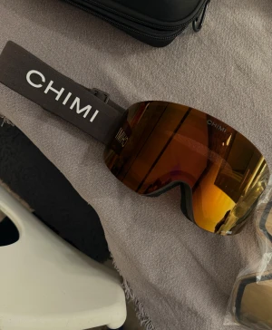 Skidglasögon  - CHIMI ski 01 Brown. Använd 3 dagar. Har en liten repa (se bilden där jag pekar) men verkligen inget som påverkar de. Helt slutsålda och nypris 1800kr.  Box osv medföljer (boxen som är på bild då, tyvärr ej kartongen då jag inte hittar den 🥲) , samt extralins! Bandet är brunt med Chimi loggan på sidorna! 🩷