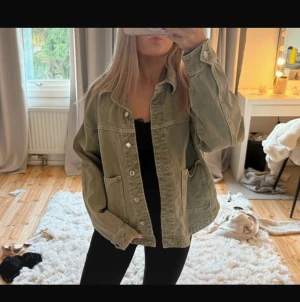 Grön jeansjacka från Zara - Säljer en grön jeansjacka från Zara med loose passform. Jackan har två stora fickor framtill, klassisk krage och knappar hela vägen. Materialet är jeans och färgen är en snygg, dov grön ton som passar till allt. Perfekt att slänga över en hoodie eller t-shirt.