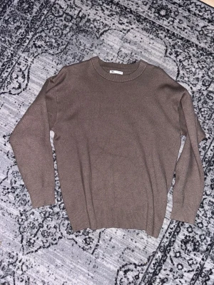 Brun stickad tröja från Zara - Snygg brun stickad tröja från Zara. Tröjan har rund halsringning, ribbade muddar vid ärmslut och nederkant samt långärmad passform. Passar även som M om man vill ha den lite lösare Perfekt för dig som gillar stilrena och enkla plagg med en chill vibe.