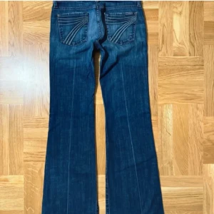 Mörkblå bootcut jeans från 7 for all mankind - Snygga mörkblå jeans från 7 for all mankind med klassisk bootcut passform. Jeansen har låg midja, fem fickor och coola detaljer på bakfickorna. Materialet är slitstarkt jeans och färgen har en lätt tvättad look. Perfekta för dig som gillar lågmifhade och annorlunda jeans. Priset är diskuterbart❗️